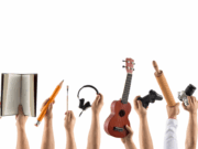 Your Athlete Is Also an Artist (And That’s a Win) Close-up of hands each holding a symbol of a different hobby or interest — such as a paintbrush, book, drumsticks, coding tablet, and sports ball — symbolizing the importance of nurturing students’ identities beyond athletics, including creative, academic, and personal pursuits.