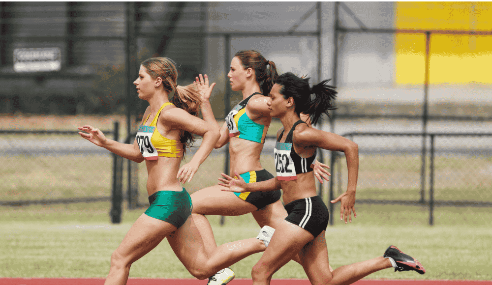 Rethinking Injury Prevention and Performance for Female Athletes Female track athletes sprinting on an outdoor track, showcasing strength, speed, and competition. The image highlights women’s athleticism in the context of research on performance, injury prevention, and equity in sports.