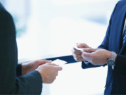 Level Up Your Leadership: Top Professional Networks for High School Athletic Directors Two athletic directors shake hands and exchange contact information, symbolizing networking and professional collaboration in school sports leadership.