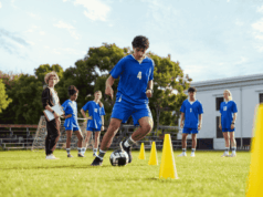 Can High School Sports Win Back the Spotlight? High school soccer players practice on a grassy field at sunset, wearing school uniforms and running drills. The image highlights the spirit of teamwork and school pride amid growing competition from private club sports programs.