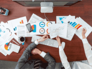 The 5 Metrics That Show True Program Health Athletic administrators reviewing performance charts and data at a desk, representing key metrics like participation, retention, GPA, injuries, and engagement that show overall athletic program health.