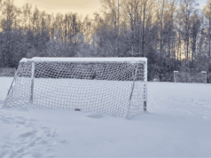 A Practical Guide to Winter Athletic Facility Maintenance A snow-covered soccer field with a goal partially buried in snow, showing an empty, wintery athletic facility with no players or activity.
