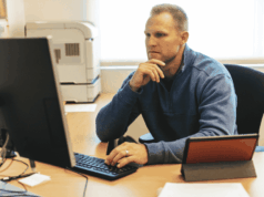 What 680 ADs Say Is Breaking the Job, and What To Do About It Athletic director reviewing reports at a desk, illustrating growing workload pressures and administrative responsibilities highlighted in a national survey of ADs.