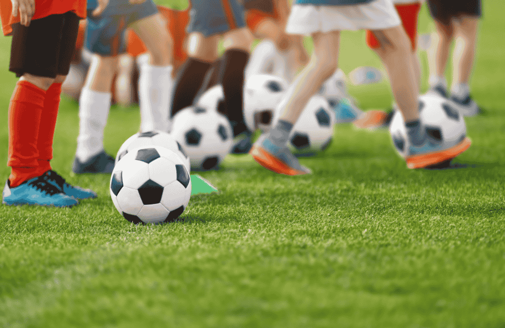 Sports camps Youth soccer camp with children practicing ball control drills on a grass field during a youth sports skills training session.